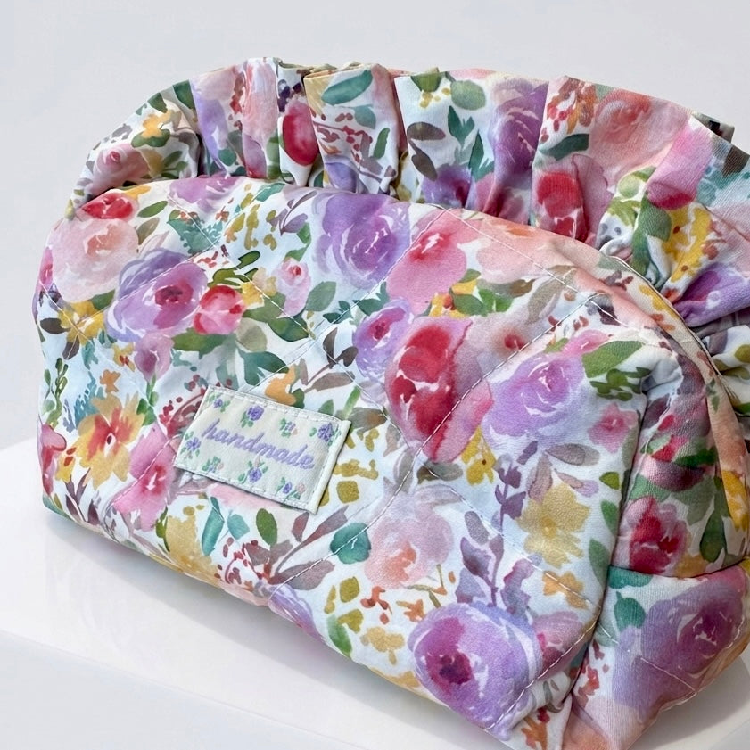Floral-patterned makeup pouch with a 'handmade' label on a white background