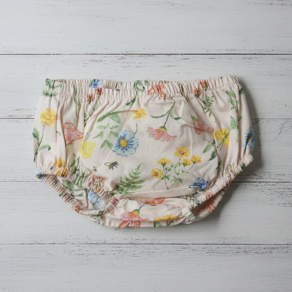 Floral-patterned baby bloomers on a light wooden surface