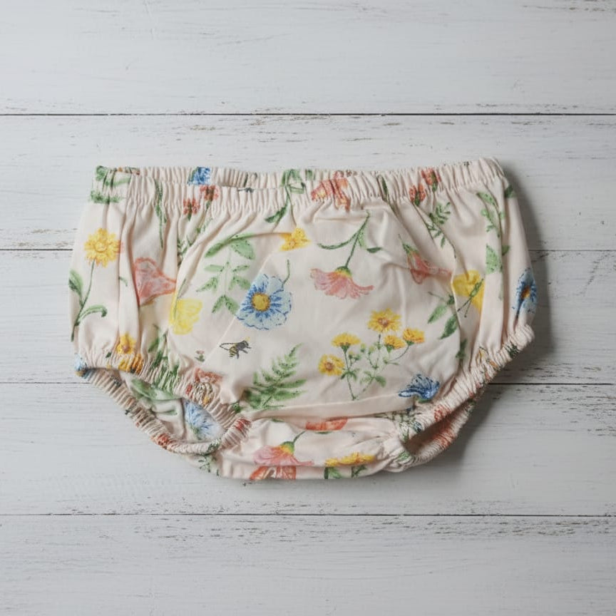 Floral-patterned baby bloomers on a light wooden surface