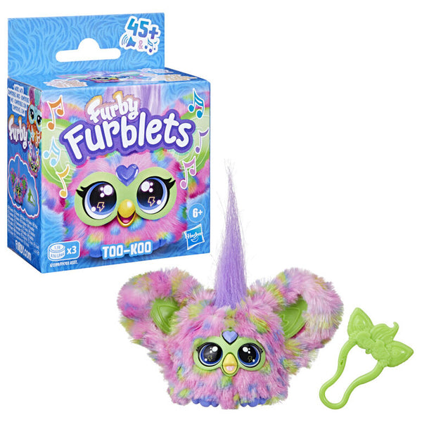 Packaging and toy version of Furby Furblets TOO-KOO with multicolored fur and a purple horn, featuring large eyes and a small keychain clip.