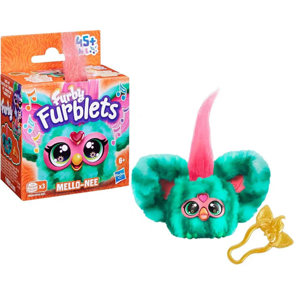 A Furby Furblets toy in green with pink ears, packaged in a product box showing the toy and 'Furbly Furblets' text.