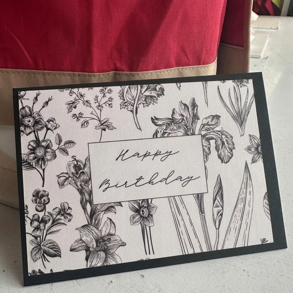 Birthday card with floral design and 'Happy Birthday' text on a white surface.