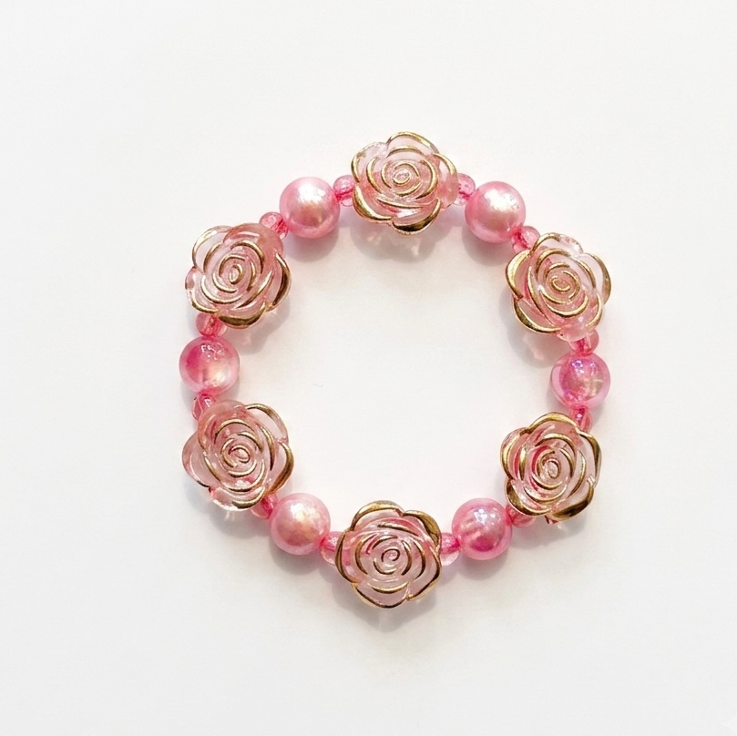 A pink and rose gold beaded bracelet featuring rose-shaped metal charms and translucent pink beads, displayed on a clean white background.