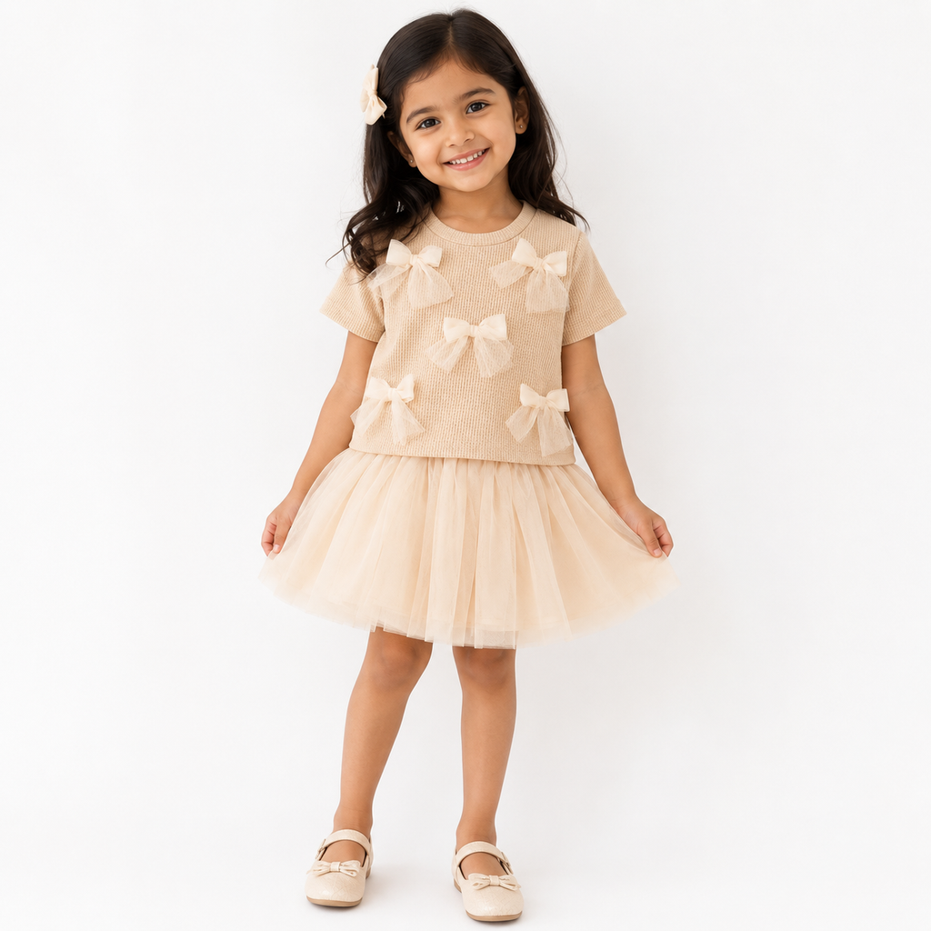 Young girl wearing a beige dress with bow details on a white background