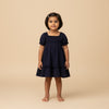 Young girl wearing a navy blue dress against a beige background