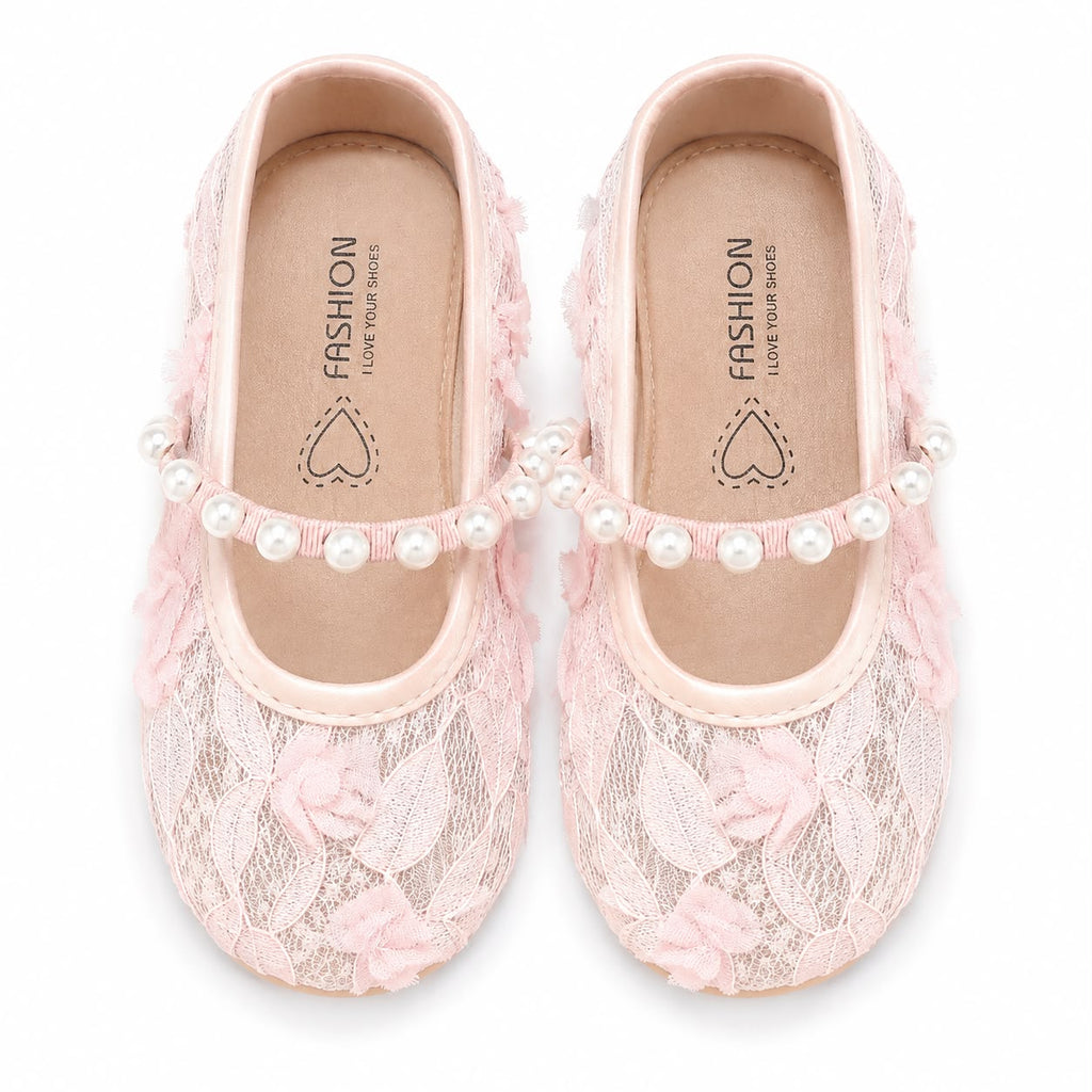 A pair of light pink lace Mary Jane flats decorated with pink fabric roses and a row of white faux pearls across the top, shown on a white background.