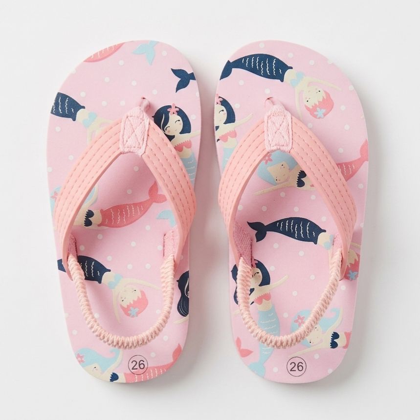 Pair of pink children's sandals with mermaid and fish pattern on a white background