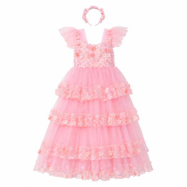 A pink girl's party dress with a matching floral headband, featuring a tiered tulle skirt and ruffled cap sleeves on a solid white background.