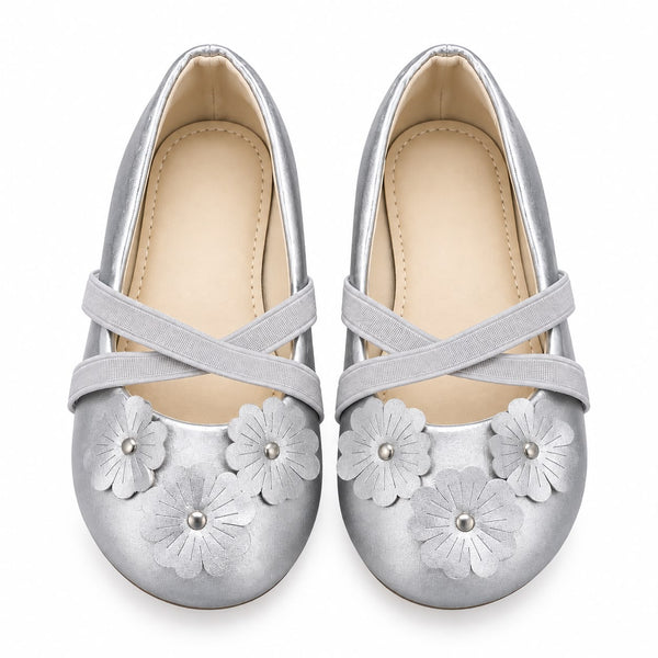 A pair of metallic silver flat shoes for girls, featuring decorative faux leather flower appliqués on the toes and crisscross elastic straps across the instep, shown against a plain white background.
