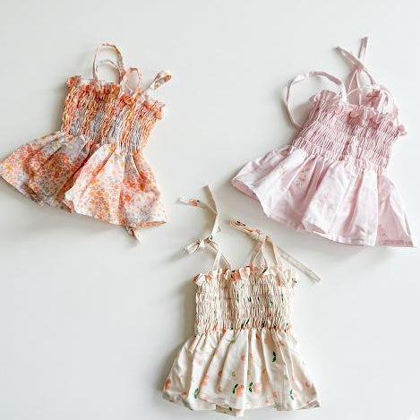 Three floral-patterned children's dresses on a white background