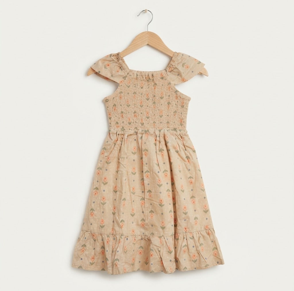 A toddler girl's sleeveless dress with ruffled cap sleeves and a tiered hem, featuring a beige base with a delicate orange and green floral pattern, hanging on a wooden hanger against a light off-white background.