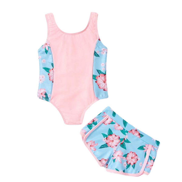 A two-piece girls' swimsuit set with a tropical print. The top is pink with a floral pattern, and the swim shorts are blue also with a floral pattern.