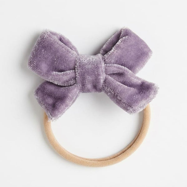 Purple velvet bow headband on a white background