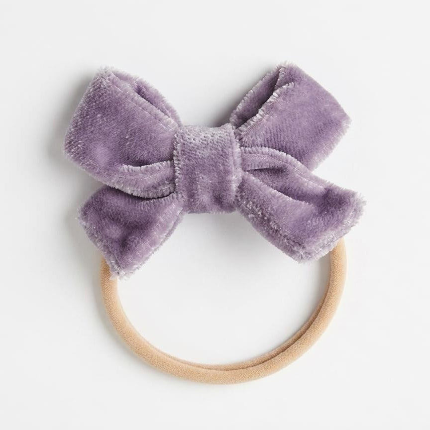 Purple velvet bow headband on a white background