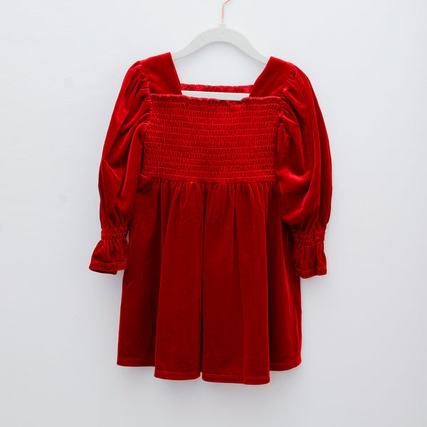 Red velvet dress on a white hanger against a white background