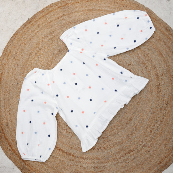 White top with colorful polka dots on a textured surface