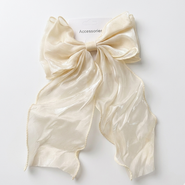 Cream-colored bow-shaped clip on a light gray background
