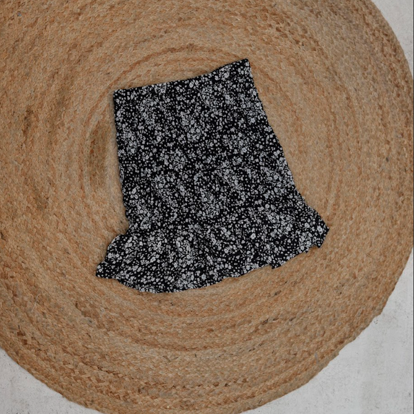 Round brown woven mat with a black and white patterned fabric piece on top