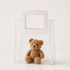 Clear plastic bag with a small brown teddy bear inside on a white background