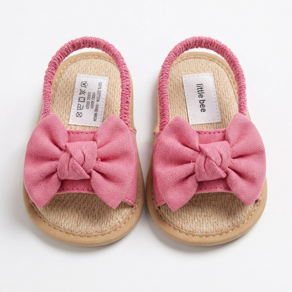Pair of baby sandals with pink bows on a white background