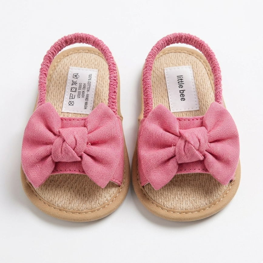 Pair of baby sandals with pink bows on a white background