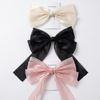 Three large decorative bows in beige, black, and pink on a white background.