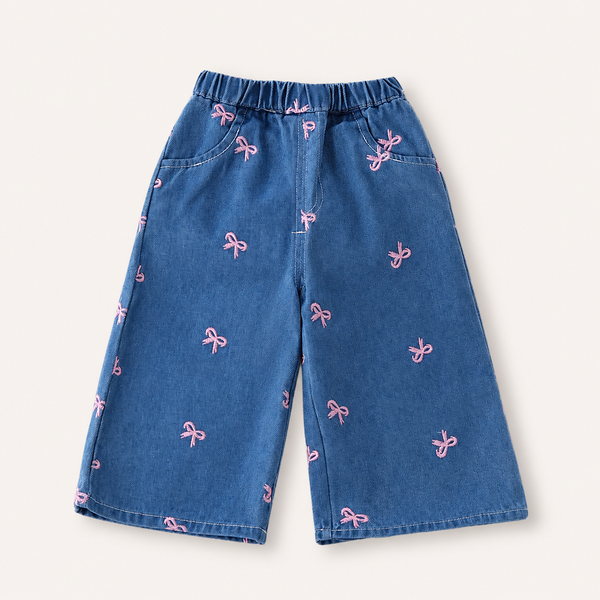 Blue denim pants with pink bow patterns on a white background