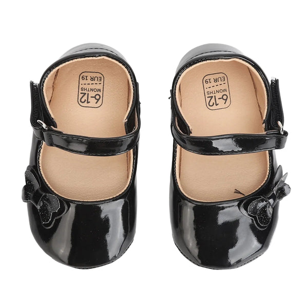 Pair of black patent leather shoes with a bow on a white background
