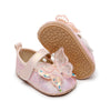 Pink glittery baby shoes with butterfly design on a white background