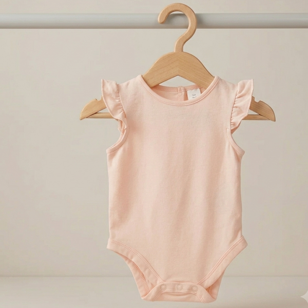 A light pink sleeveless baby bodysuit with ruffled shoulder details, hanging on a wooden hanger from a clothing rack against a neutral cream background.