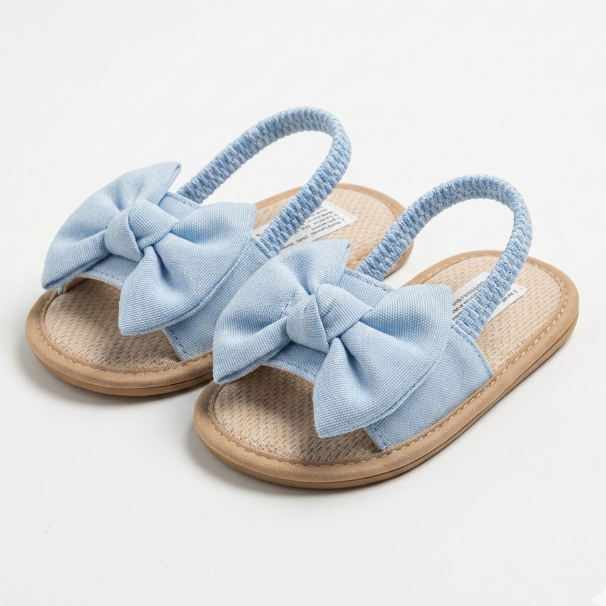 Pair of light blue sandals with bow details on a white background