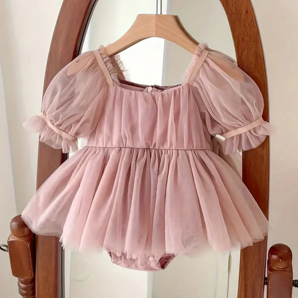 Pink baby dress with sheer sleeves on a wooden hanger against a neutral background