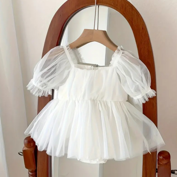 White tulle dress on a wooden hanger against a neutral background