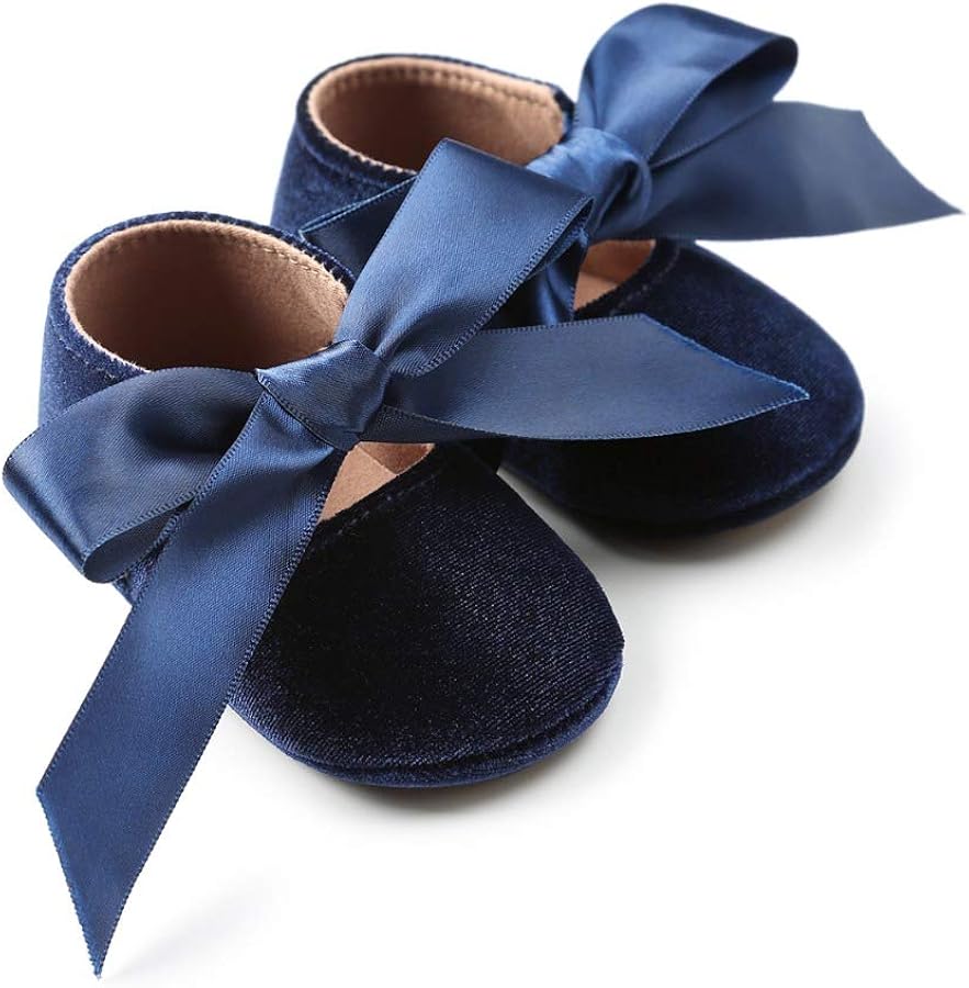 Navy blue baby shoes with large satin bows on a white background
