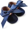 Navy blue baby shoes with large satin bows on a white background