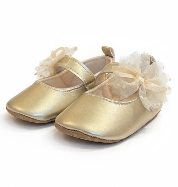 Gold baby shoes with white bows on a white background