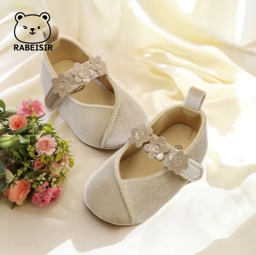 Pair of beige baby shoes with floral straps on a soft white background, featuring the RABEISIR brand.
