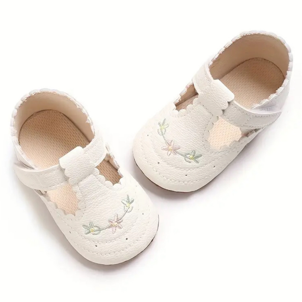 White baby shoes with floral embroidery on a white background