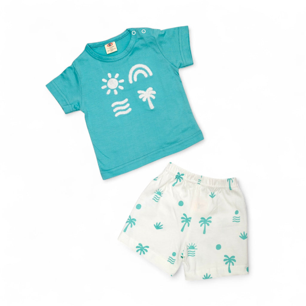 Children's turquoise shirt with white graphics and white shorts with palm tree pattern on a white background