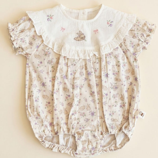 Floral baby romper with ruffled collar on a beige background