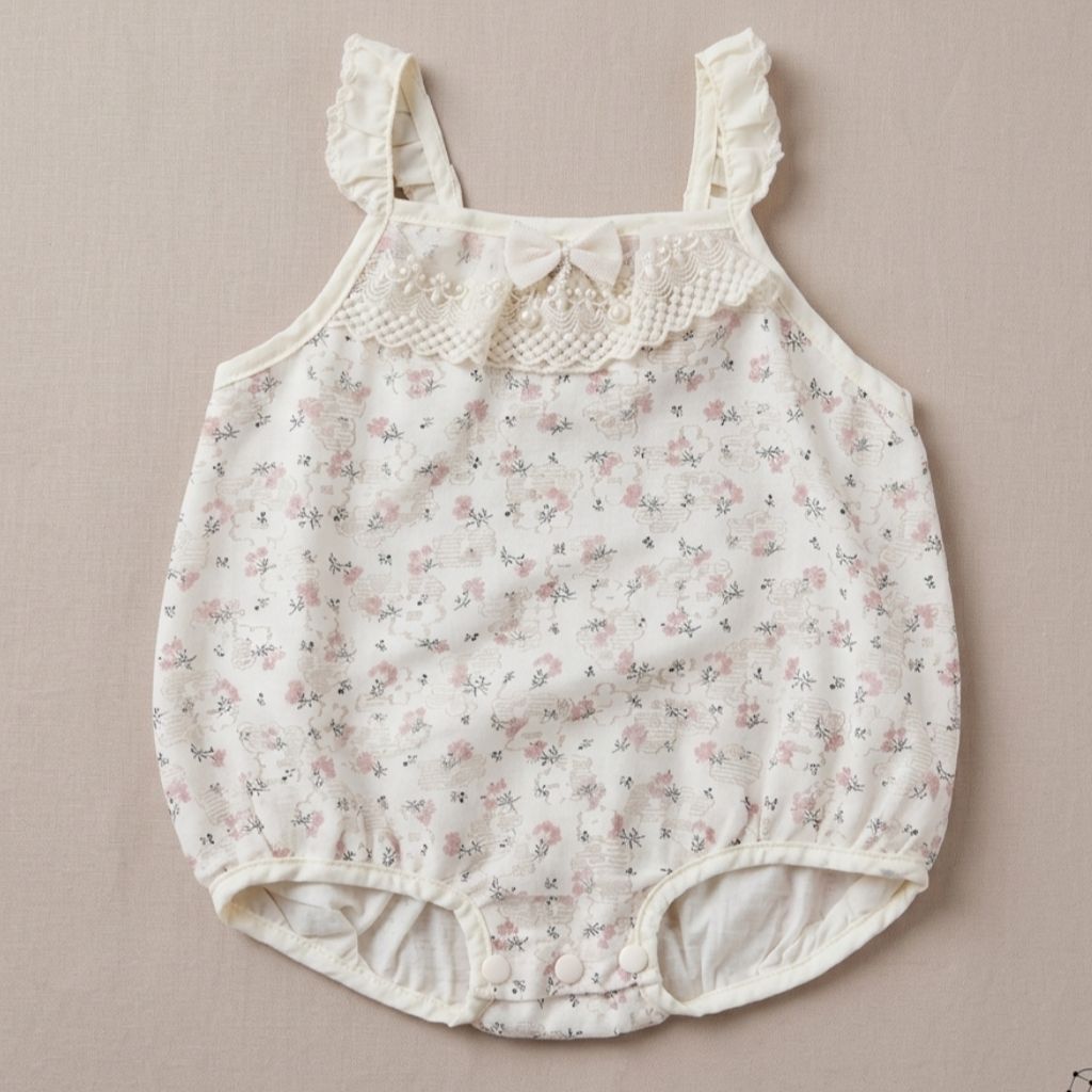 Floral baby romper with lace details on a beige background