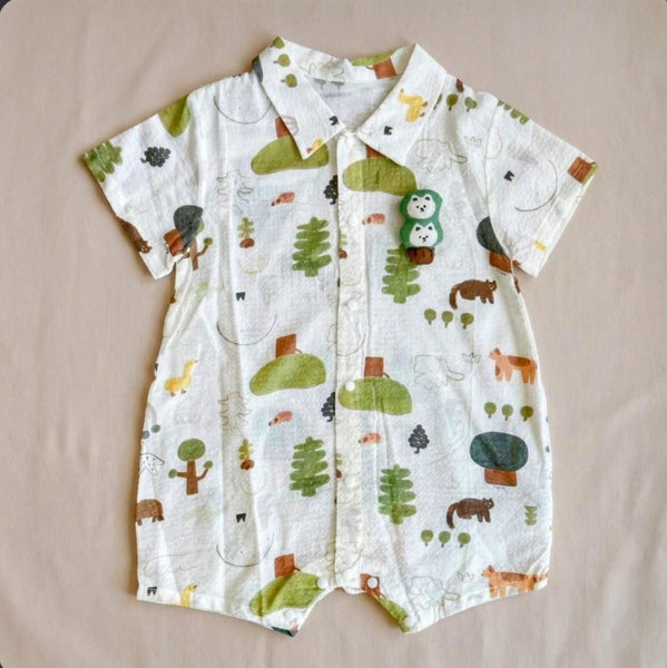 Baby romper with animal and nature pattern on a beige surface