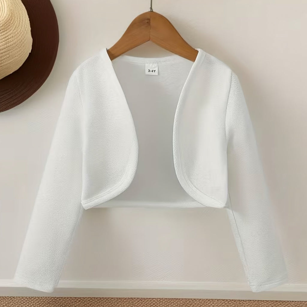 White children's shrug on a wooden hanger against a beige background 