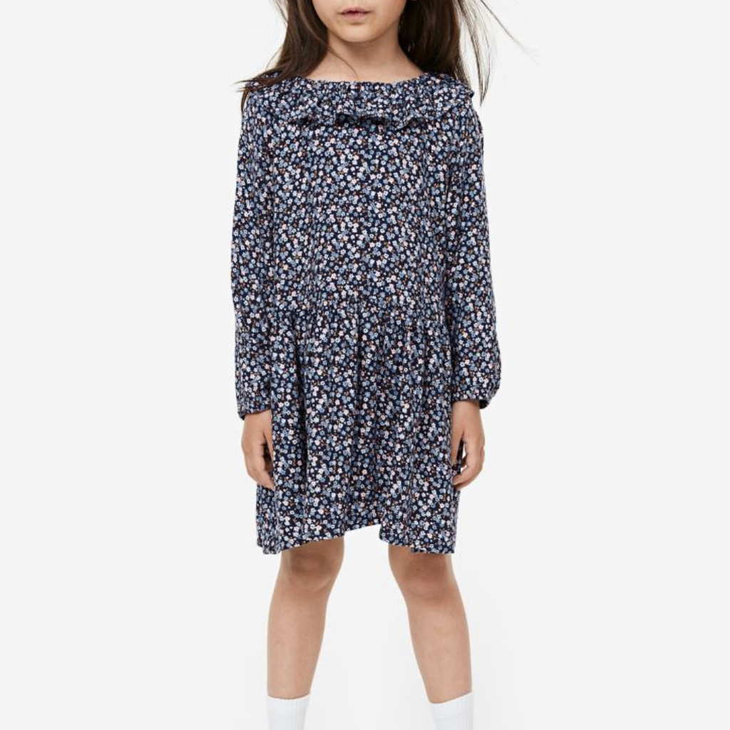 A girl wearing a navy floral print dress with short sleeves and a flowing skirt.