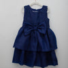 Navy blue dress with a large bow on a white hanger against a light gray background