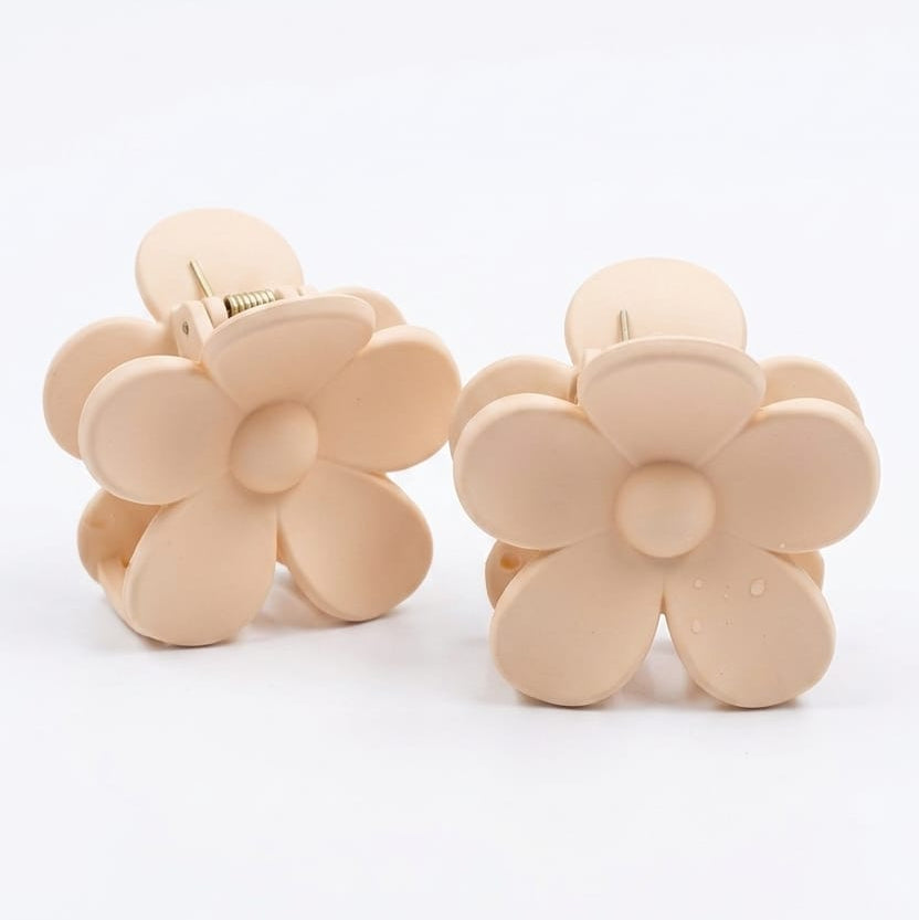 Pair of beige flower-shaped hair clips on a white background