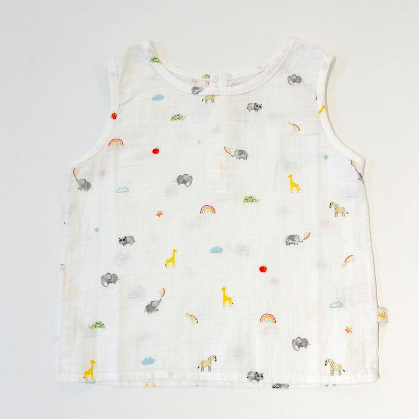 A white muslin vest for babies with a rainbow and elephant pattern.