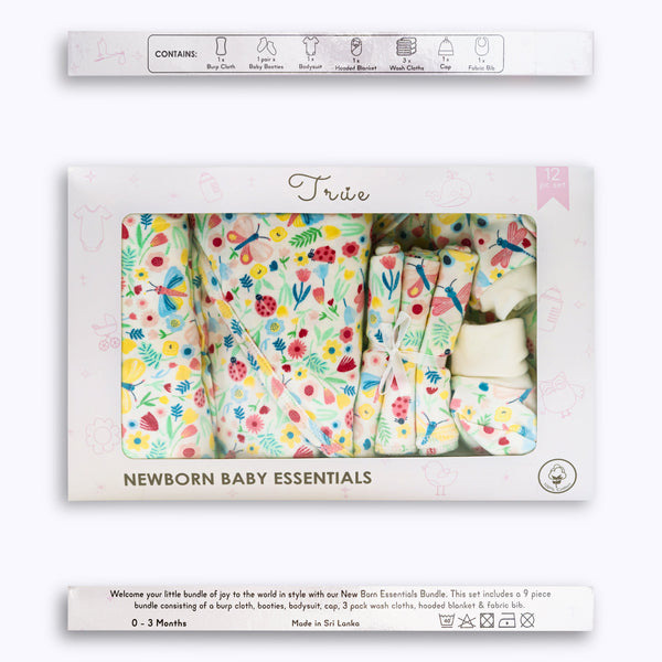A 12-piece newborn essentials bundle with a floral pattern, displayed in an open box with items such as burp cloths, baby mittens, booties, a onesie, a cap, wash cloths, a hooded blanket, a swaddle blanket, and a fabric bib.