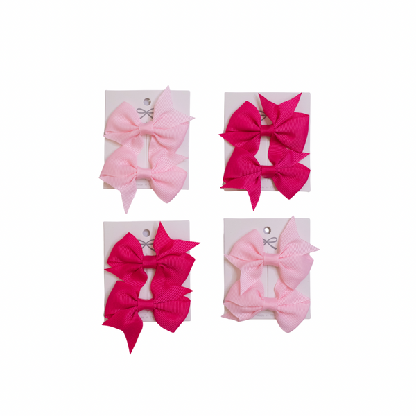 Four pink and red hair bows on a white background