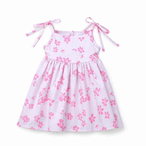 Flat lay of a light pink baby girl dress featuring a bright pink floral print and delicate tie-shoulder straps.
